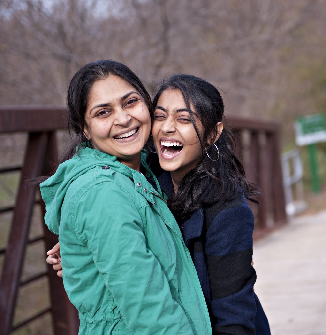 a mother and her daughter embracing on a quaint bridge